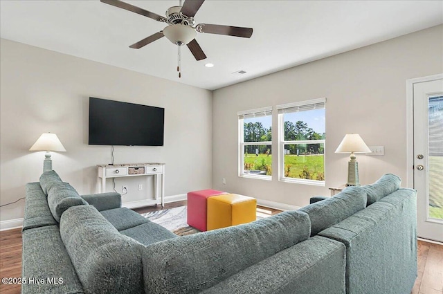 living area featuring wood finished floors, visible vents, baseboards, and a ceiling fan