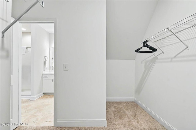 spacious closet with light colored carpet and lofted ceiling