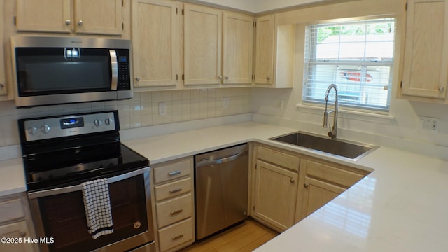 kitchen featuring a sink, appliances with stainless steel finishes, light brown cabinetry, and light countertops