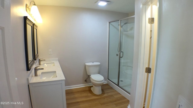 full bathroom featuring a sink, a stall shower, toilet, and wood finished floors