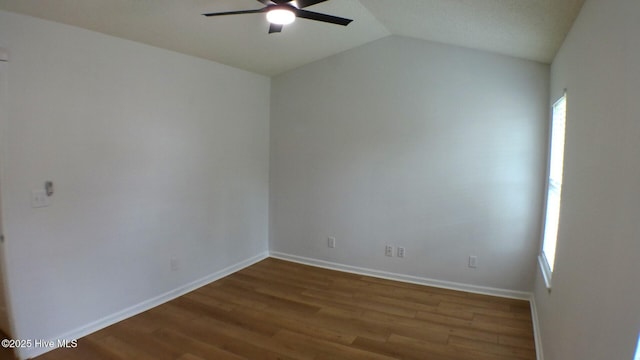 spare room featuring baseboards, a ceiling fan, wood finished floors, and vaulted ceiling