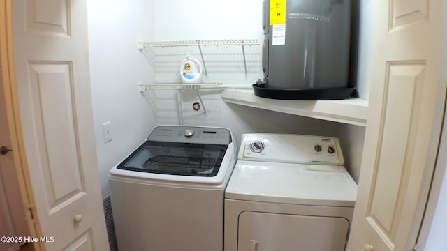 laundry area with laundry area, washer and clothes dryer, and electric water heater
