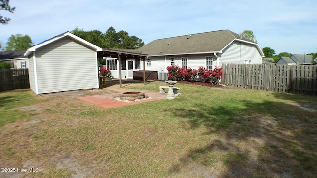rear view of house featuring an outdoor fire pit, a patio, a fenced backyard, a lawn, and a hot tub