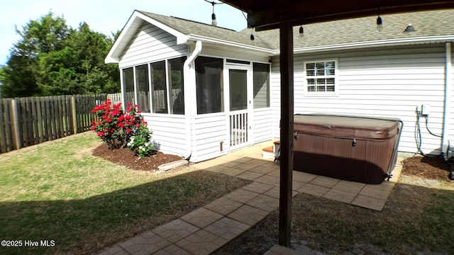 view of property exterior with roof with shingles, a patio area, a sunroom, a hot tub, and a fenced backyard
