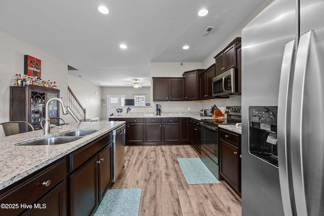 kitchen featuring dark brown cabinetry, a sink, light wood finished floors, stainless steel appliances, and visible vents