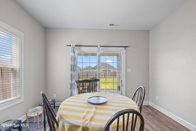 dining space with visible vents, baseboards, and wood finished floors