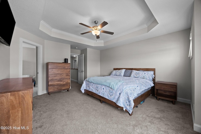 bedroom featuring a ceiling fan, baseboards, ornamental molding, a tray ceiling, and carpet flooring