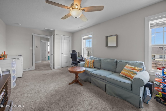 living area with carpet floors, ceiling fan, baseboards, and a healthy amount of sunlight