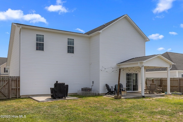 rear view of property featuring a yard, fence, and a patio area