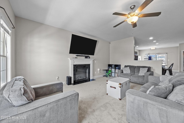living area featuring a ceiling fan, light colored carpet, a fireplace with flush hearth, baseboards, and recessed lighting