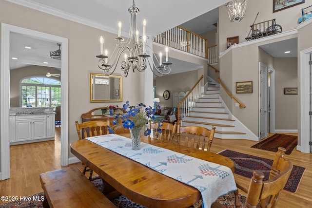 423 Black Diamond Dr, Wilmington, NC 28411 - dining room with baseboards, light wood-style floors, a towering ceiling, ceiling fan with notable chandelier, and stairs