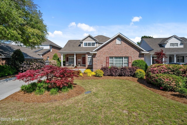 423 Black Diamond Dr, Wilmington, NC 28411 - view of front of house with a front yard, a shingled roof, brick siding, and covered porch
