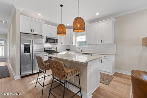 119 Bridgetowne Ave, Edenton, NC 27932 - kitchen featuring appliances with stainless steel finishes, light wood finished floors, white cabinetry, and a kitchen island