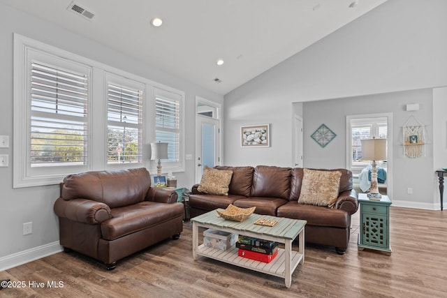 living room with baseboards, recessed lighting, visible vents, high vaulted ceiling, and wood finished floors