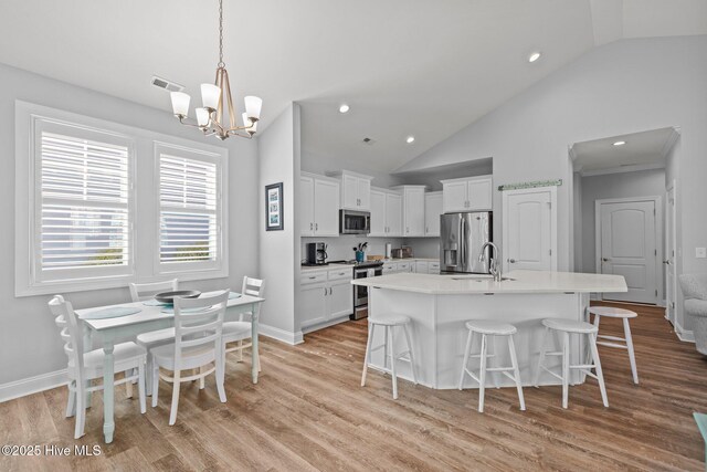 kitchen with white cabinetry, appliances with stainless steel finishes, a breakfast bar, and an inviting chandelier