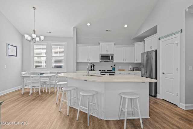 kitchen featuring stainless steel appliances, an inviting chandelier, a kitchen breakfast bar, and a sink