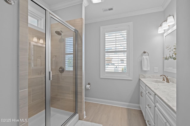 bathroom featuring crown molding, a shower stall, vanity, visible vents, and baseboards