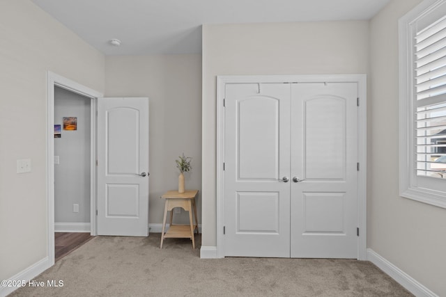 carpeted bedroom featuring a closet and baseboards