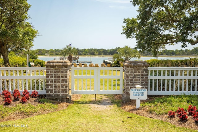 view of gate with fence and a water view