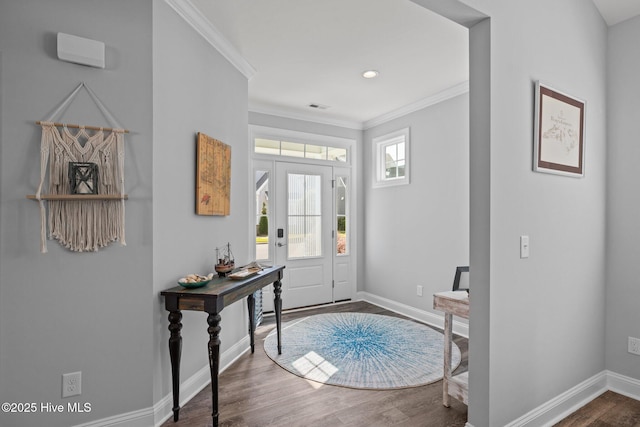 foyer entrance featuring crown molding, wood finished floors, baseboards, and visible vents