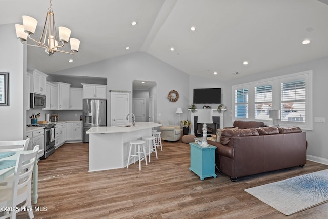 living area featuring light wood-style floors, high vaulted ceiling, a notable chandelier, and recessed lighting