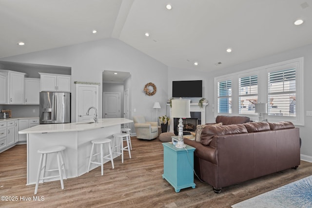 living area featuring light wood-type flooring, a fireplace, and vaulted ceiling