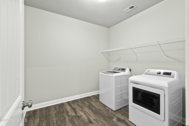 clothes washing area with baseboards, visible vents, laundry area, dark wood finished floors, and washer and dryer