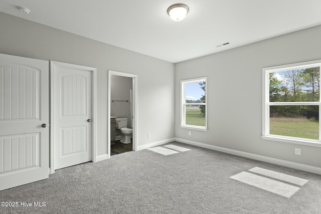unfurnished bedroom with visible vents, baseboards, carpet flooring, and ensuite bath