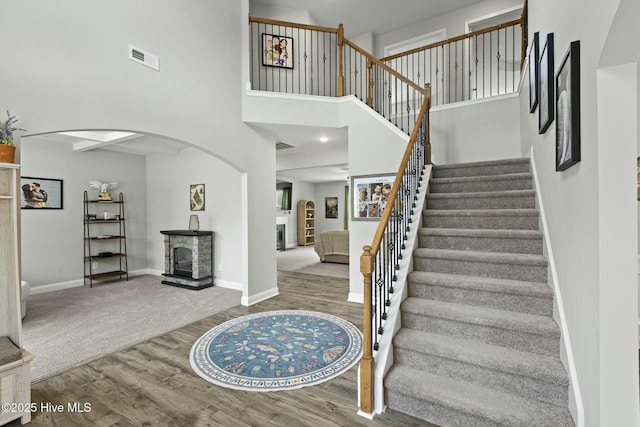 stairway with visible vents, baseboards, wood finished floors, and a fireplace