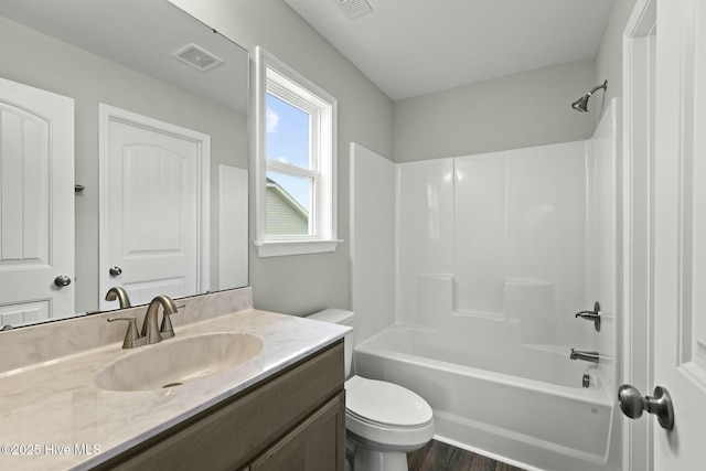 bathroom with visible vents, toilet, vanity, wood finished floors, and shower / bath combination