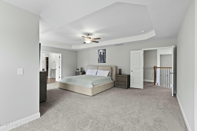 unfurnished bedroom with carpet flooring, visible vents, a tray ceiling, and baseboards
