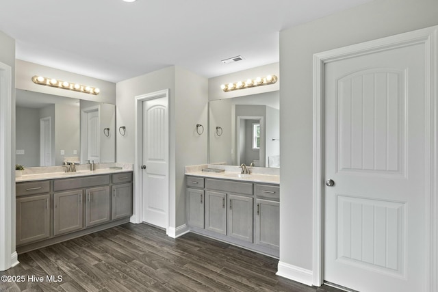 bathroom with a sink, visible vents, two vanities, and wood finished floors