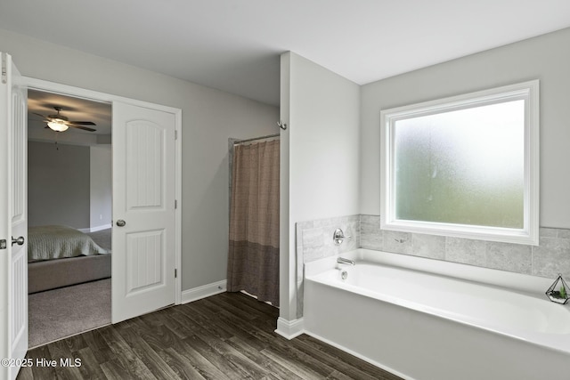 ensuite bathroom with ceiling fan, connected bathroom, a bath, wood finished floors, and baseboards