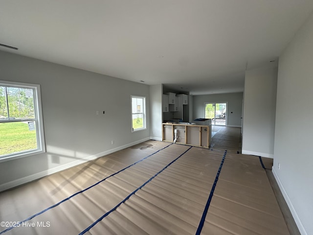 unfurnished living room with baseboards