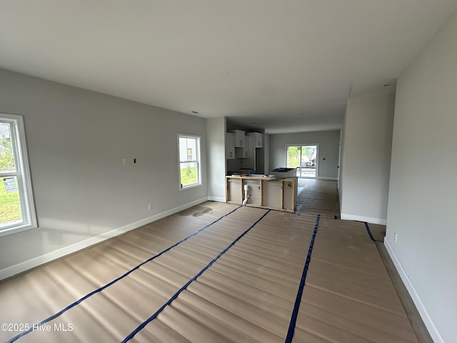 unfurnished living room with baseboards