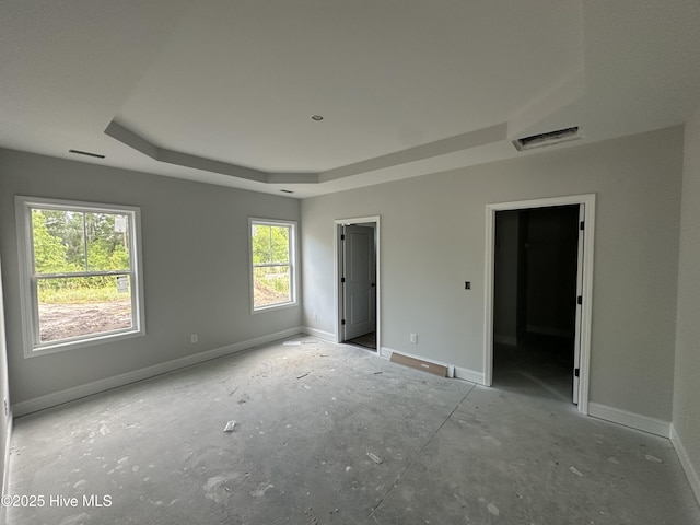 unfurnished bedroom with a tray ceiling, baseboards, and visible vents