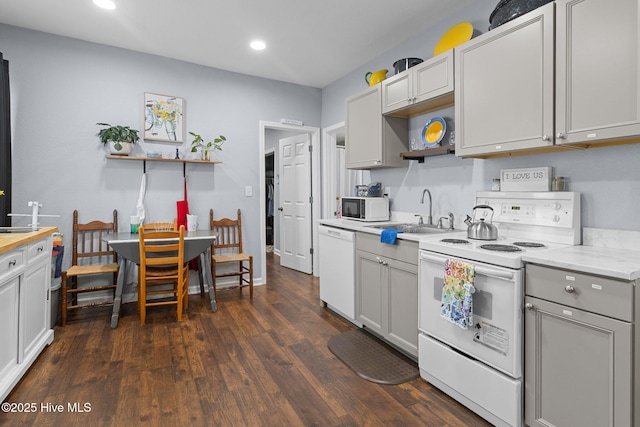 kitchen featuring open shelves, a sink, white appliances, recessed lighting, and dark wood-type flooring