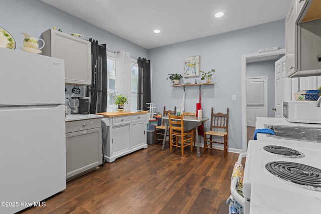 kitchen featuring dark wood-type flooring, butcher block counters, white appliances, and recessed lighting