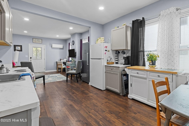 kitchen featuring freestanding refrigerator, dark wood-style floors, recessed lighting, and a wall mounted air conditioner