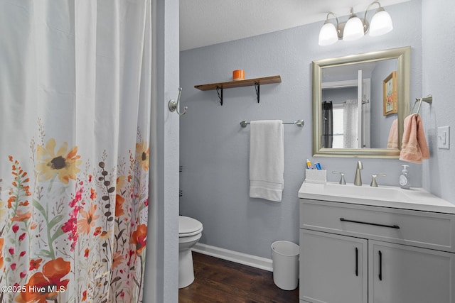 bathroom with vanity, toilet, wood finished floors, a shower with shower curtain, and baseboards