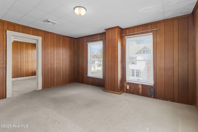 spare room with visible vents, carpet flooring, and wood walls