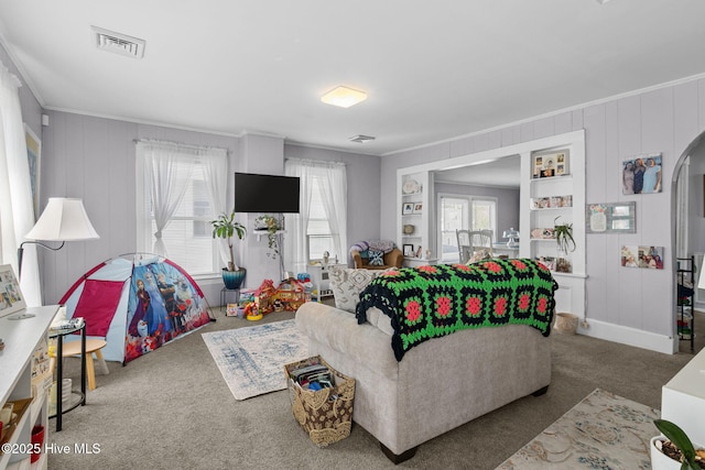 carpeted living area featuring crown molding, visible vents, and arched walkways