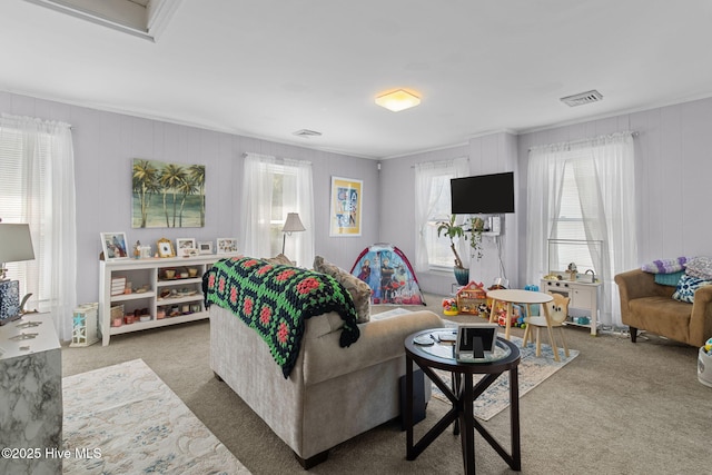 living area with visible vents, ornamental molding, and carpet