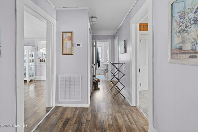 hall featuring wood finished floors, baseboards, and visible vents