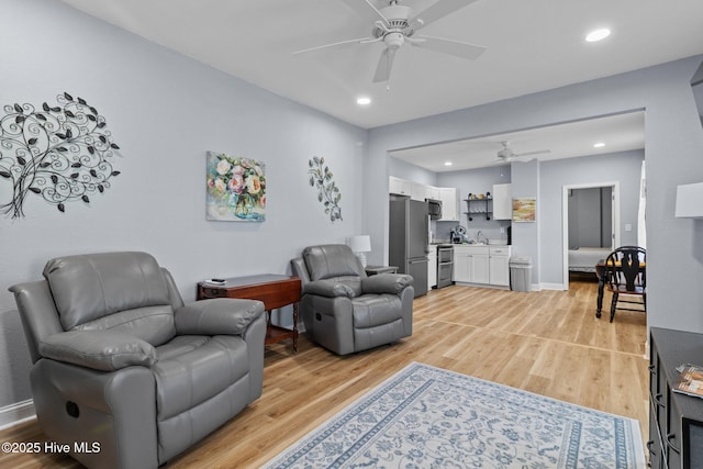 living room with light wood finished floors, baseboards, a ceiling fan, and recessed lighting