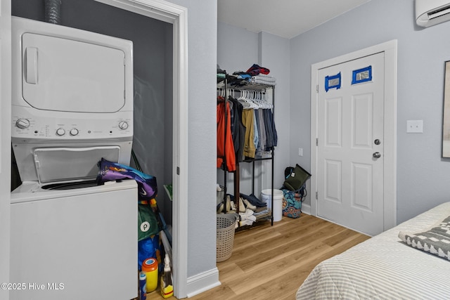 clothes washing area with laundry area, wood finished floors, stacked washer and clothes dryer, and a wall mounted air conditioner
