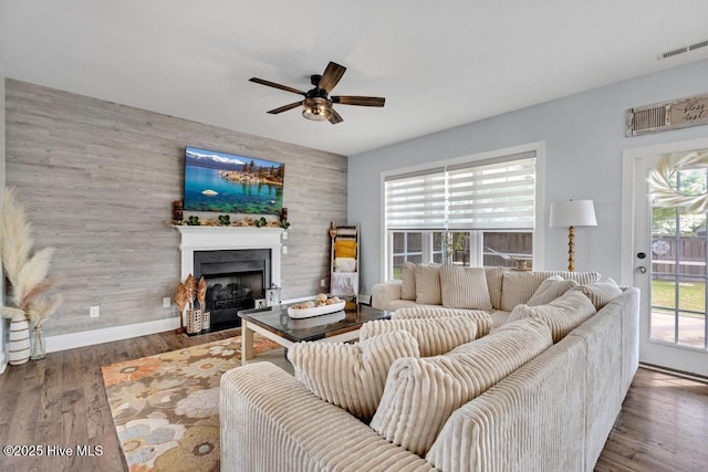 41 S Lamplighters Walk, Hampstead, NC 28443 - living room featuring a ceiling fan, a fireplace with flush hearth, wooden walls, wood finished floors, and baseboards