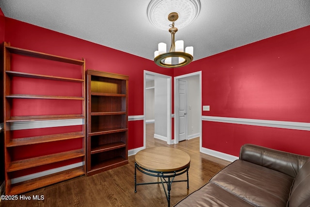 living room featuring a textured ceiling, wood finished floors, and baseboards