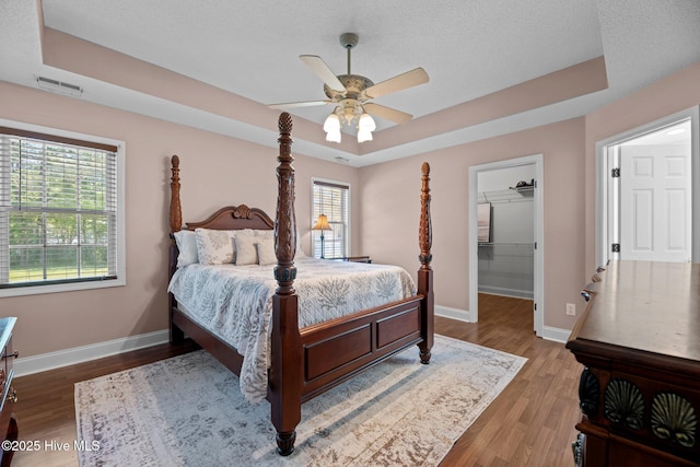 bedroom with multiple windows, baseboards, and a raised ceiling