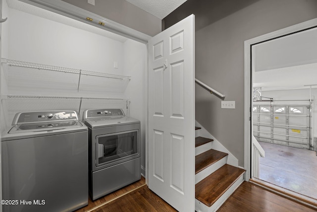 clothes washing area featuring dark wood-type flooring, washer and dryer, and laundry area